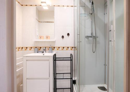 a white bathroom with a shower and a sink at La Clé des Sternes in Camiers