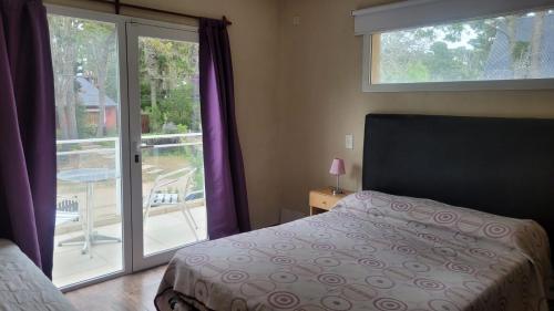 a bedroom with a bed and a sliding glass door at Lihuen in Mar Azul