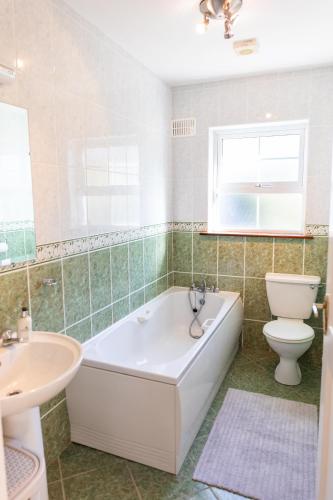 a bathroom with a tub and a toilet and a sink at Wild Atlantic Hideaway in Doolin