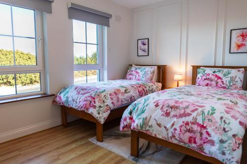 a bedroom with two beds and two windows at Wild Atlantic Hideaway in Doolin
