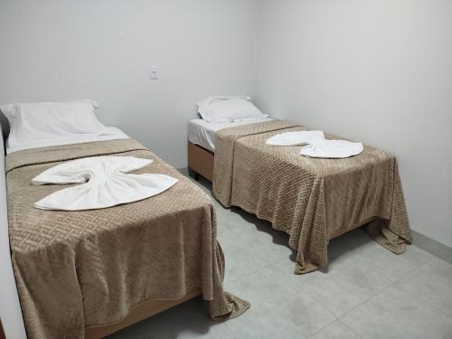two beds with blankets and towels on them in a room at DSá Hotel in Cristalândia