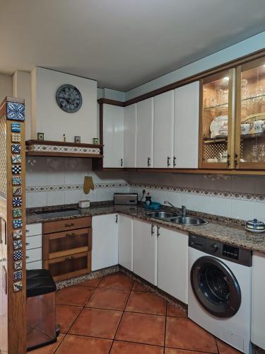 a kitchen with white cabinets and a washing machine at Casa Kamelias in Moraña