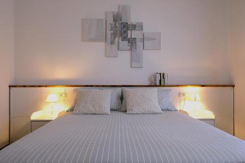 a white bed with two lamps on both sides of it at Holiday Vibes in Pisa