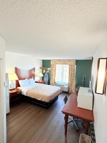 a bedroom with a bed and a table and a desk at Three Rivers Motel in Fort Wayne
