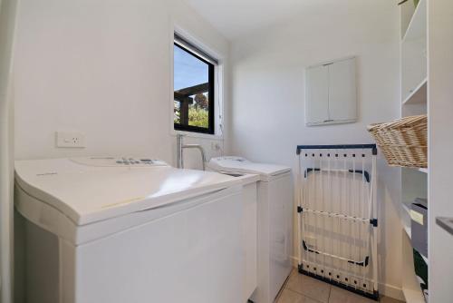 a white bathroom with a sink and a window at Chartres Retreat in Arrowtown