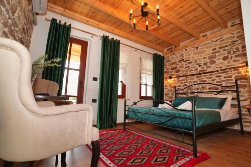 a bedroom with a bed with green curtains and a chair at Alchemist Inn in Gjirokastër