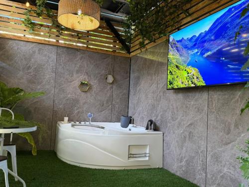 a bathroom with a tub and a tv on a wall at Estadía con opción jacuzzi Villa Alemana in Villa Alemana