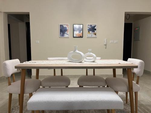 a dining room table with chairs and vases on it at Quiet Comfy Stay in Burg el-Ḥudûd