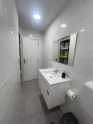 a white bathroom with a sink and a mirror at Casa São Marcos II in Peniche