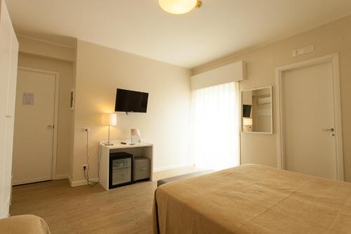 a bedroom with a bed and a television on a wall at Hotel Costazzurra Museum & Spa in San Leone