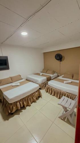 a room with three beds and a tv in it at HOTEL DULCES SUEÑOS N°2 in Tuluá