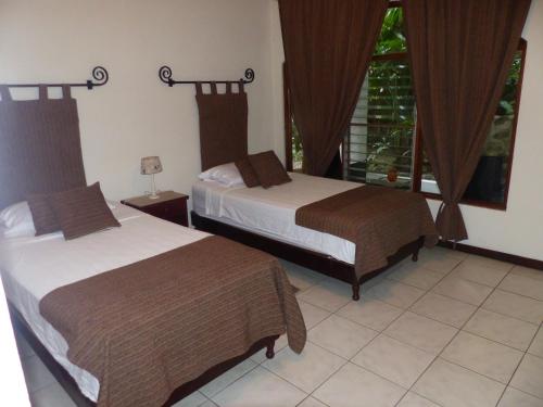 a hotel room with two beds and a window at Hotel Villa Romantica in Manuel Antonio