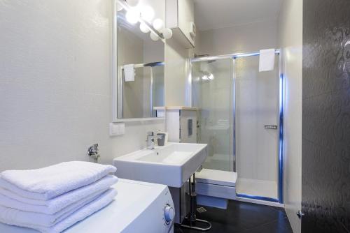 a white bathroom with a sink and a shower at Apartments Niko in Cavtat