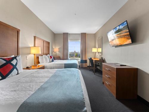 a hotel room with two beds and a desk at The Kanata Bonnyville in Bonnyville