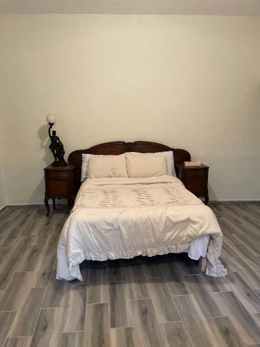 a bedroom with a bed with white sheets and wooden floors at Yellow House, Private Apartment, Centro Arteaga in Arteaga