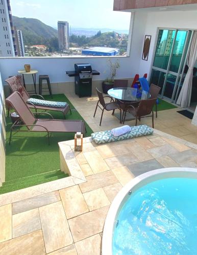 a patio with a pool and a table and chairs at Cobertura Espetacular no Belvedere com Jacuzzi in Belo Horizonte