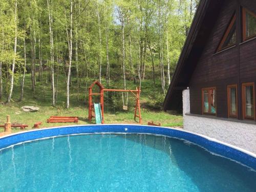 a swimming pool in front of a house with a playground at Studio with Pool in Benecko-Riesengebirge 2218 in Benecko