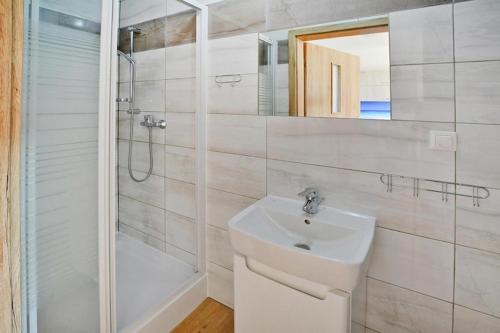 a white bathroom with a sink and a shower at Comfortable holiday homes with a summer pool in Jarosławiec