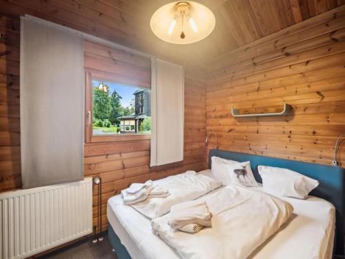 a bed in a room with a wooden wall at Finnische Blockhausstilhäuser im Harz in Benneckenstein