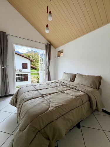 a bedroom with a large bed and a large window at BeInn - Short Stay Collection Penedo in Itatiaia