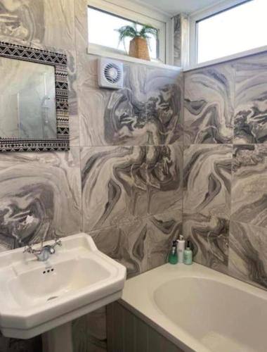 a bathroom with a sink and a tub and a mirror at Central location Sea view in Hastings