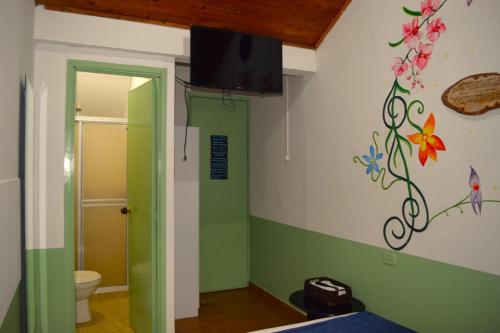 a bathroom with a green and white wall with flowers on the wall at FILANDIA HOTEL in Filandia