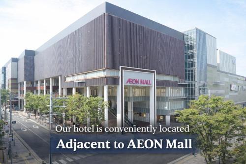 an office building with a sign that reads our hotel is conveniently located adjacent to at GLANZ KEI Kyoto Station in Kyoto
