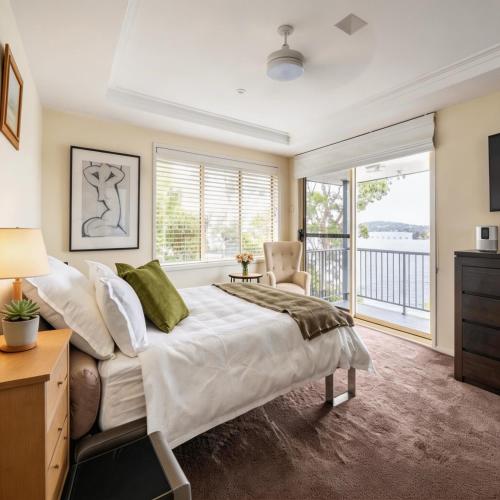 a bedroom with a large bed and a balcony at Stunning Absolute Waterfront With Private Jetty in Fishing Point