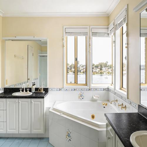 a bathroom with a tub and two sinks and a large window at Stunning Absolute Waterfront With Private Jetty in Fishing Point