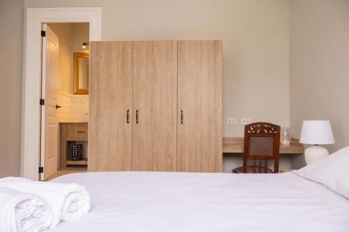 a bedroom with a white bed and a wooden cabinet at Casa Cáceres in Lima