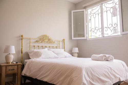 a bedroom with a bed with white sheets and a window at Casa Cáceres in Lima