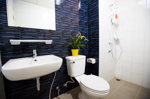 a bathroom with a toilet and a sink with a plant on it at Room 9 Residence in Pluak Daeng