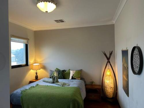 a bedroom with a bed with green sheets and a window at Midby's Elegant Guesthouse - 2 En-suite Rooms & 2 Rooms with Shared Bathroom in Perth