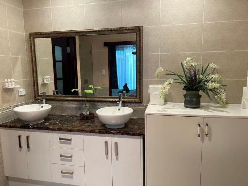 a bathroom with two sinks and a mirror at Midby's Elegant Guesthouse - 2 En-suite Rooms & 2 Rooms with Shared Bathroom in Perth