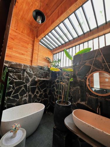a bathroom with two sinks and a stone wall at Villa Cô Ba 2 in Da Thanh