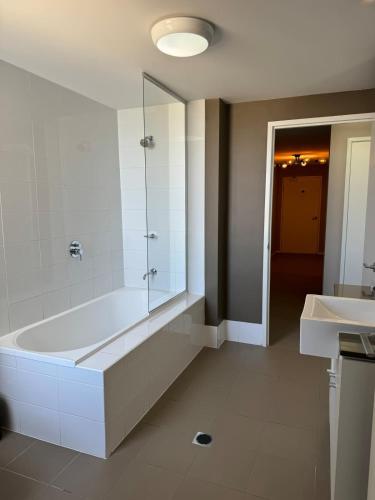 a bathroom with a tub and a shower and a sink at The Perfect Host @ Curtis Apartments in Gladstone