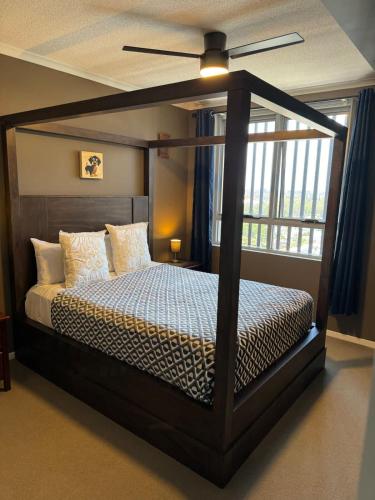 a bedroom with a canopy bed and a window at The Perfect Host @ Curtis Apartments in Gladstone