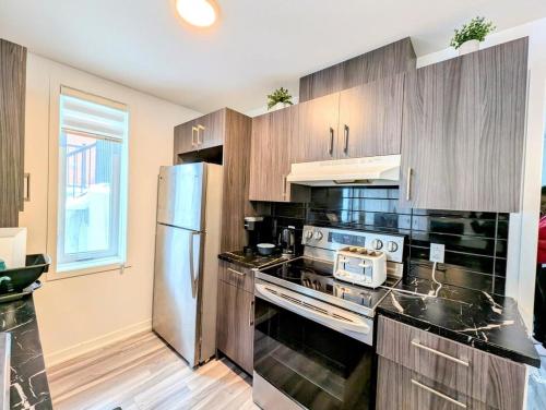 a kitchen with wooden cabinets and a stainless steel refrigerator at Cozy 1BR Apt perfect for Couple in Longueuil