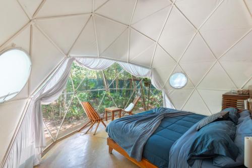 a bedroom with a tent with a bed and a window at Jungle Glamping K'u' Kuk in Chemuyil