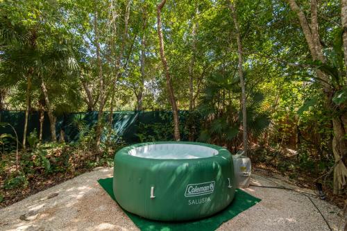a green tub sitting on the ground in front of trees at Jungle Glamping K'u' Kuk in Chemuyil
