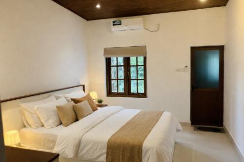 a bedroom with a large white bed with a window at Citron Cottage in Kandy