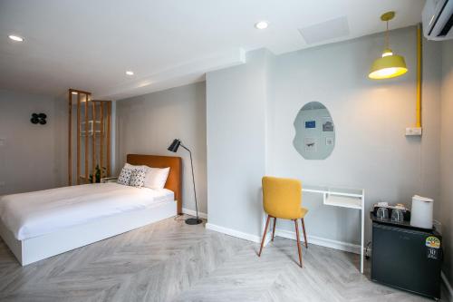 a bedroom with a bed and a yellow chair at Siri Space สิริ สเปซ in Ban Khlong Nung (1)