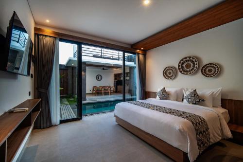 a bedroom with a large bed and a balcony at Alima Villa Ubud in Ubud