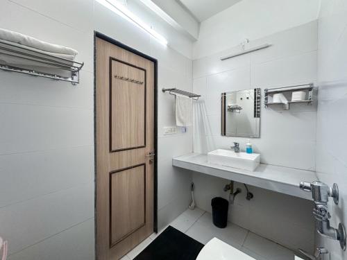a bathroom with a wooden door and a sink at NIVANTA-CREAZE by Bendre's in Kārli