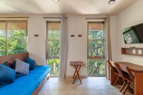 a living room with a blue couch and a table at Jungle Loft Suite with Terrace & Natural Light - Santuario Hotel Boutique in Chemuyil