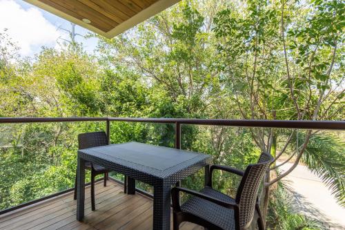 a table and chairs on a balcony with trees at Jungle Loft Suite with Terrace & Natural Light - Santuario Hotel Boutique in Chemuyil