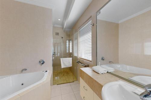 a bathroom with a tub and a sink at 6 Colonial in Noosaville