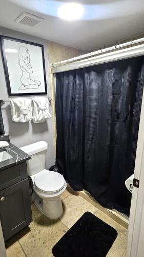 a bathroom with a toilet and a black shower curtain at Super Cozy 2 bedroom with Fast WIFI and Queen Bed close to Downtown Houston!! in Houston