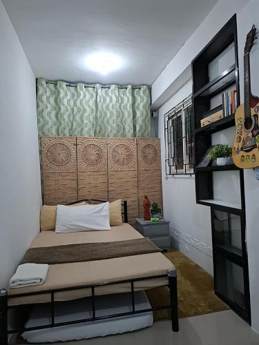 a bedroom with a bed with a headboard and a guitar at Lancaster new city in General Trias