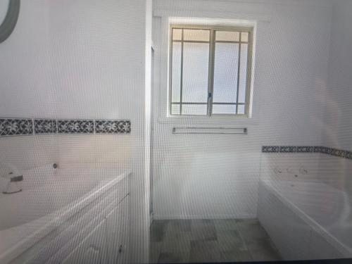 a white bathroom with a tub and a window at Millingtons Beach House in Orford